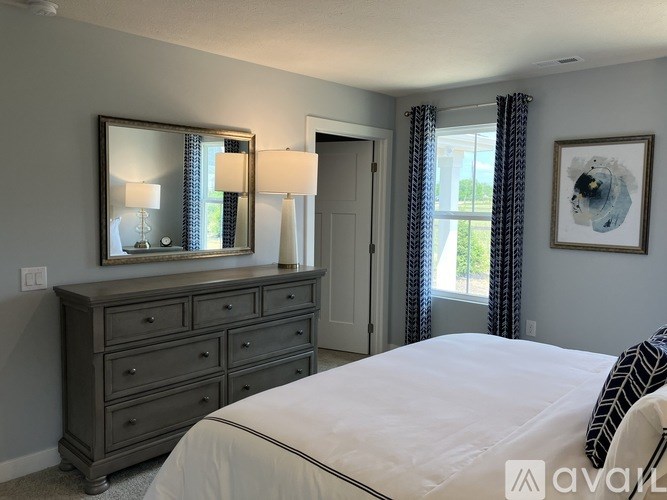 A bedroom with a large bed, a dresser with a mirror, and a window with curtains.