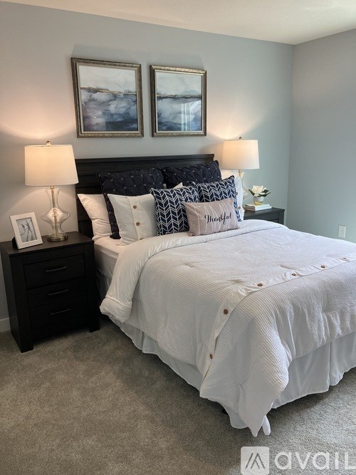 A bedroom with a large bed and two framed pictures on the wall.