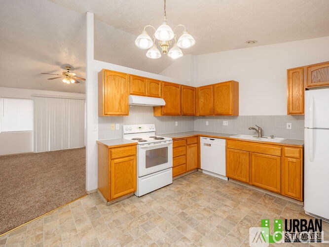 A kitchen with wooden cabinets and a white stove top oven.