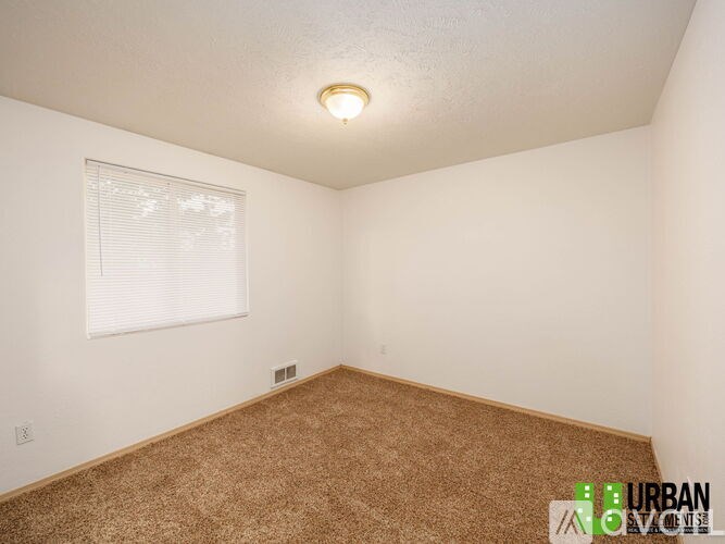 A room with a carpeted floor and a window with blinds.