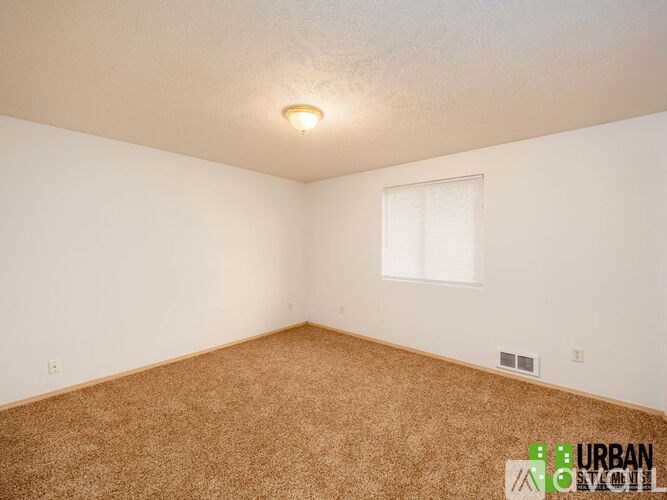 A room with a carpeted floor and a window.