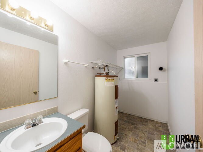 A bathroom with a toilet, sink, and mirror.