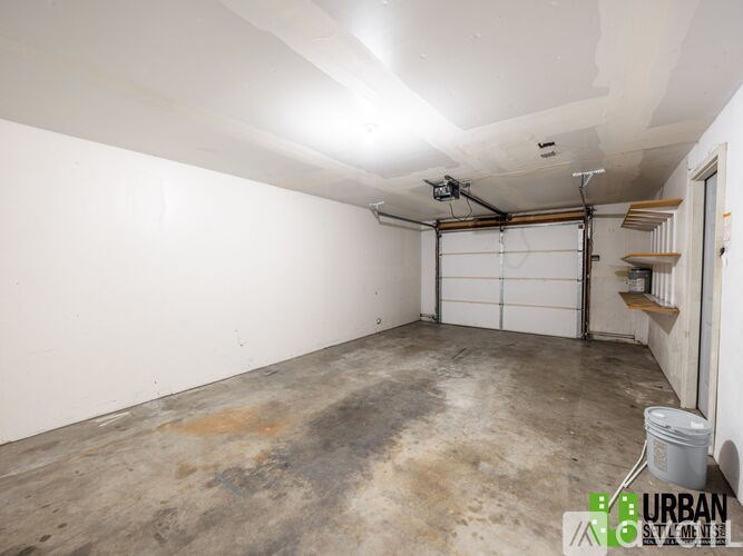 A large empty room with a white ceiling and a white door.