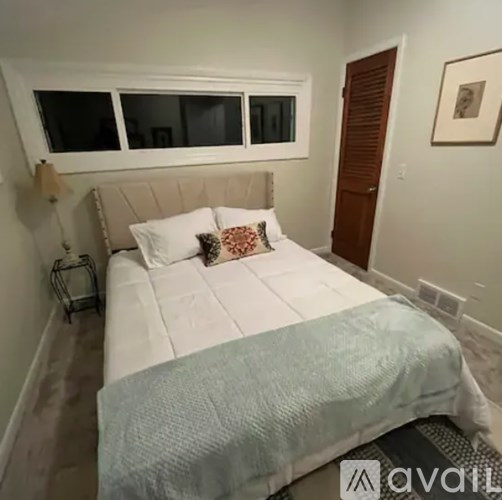 A bedroom with a bed, pillows, and a lamp.