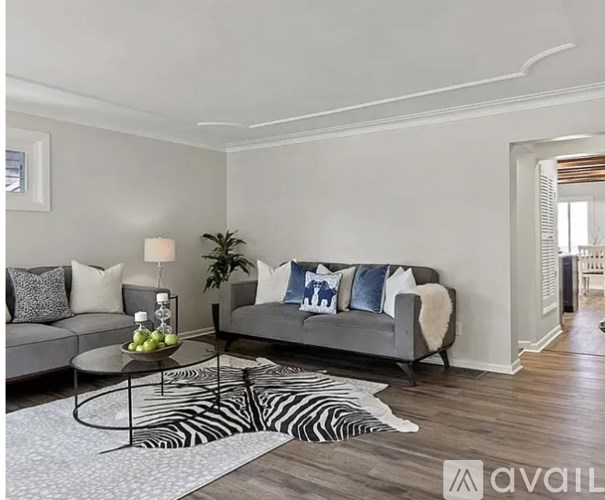 A living room with a grey couch, a zebra rug, and a coffee table with fruit on it.