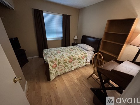 A bedroom with a floral bedspread and a wooden chair.