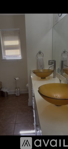 A bathroom with two yellow sinks and a mirror.