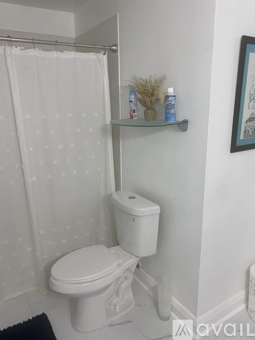 A white toilet with a white shower curtain with holes in it.