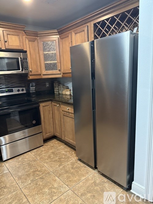 A kitchen with a stainless steel refrigerator and wooden cabinets.