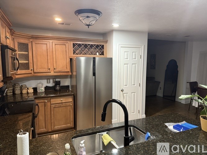 A kitchen with a granite countertop and a stainless steel refrigerator.