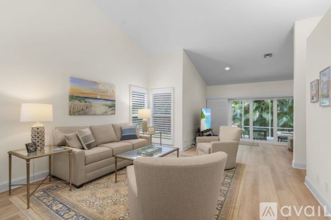 A living room with a beige couch, a glass table, and a painting on the wall.