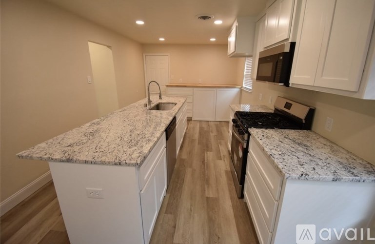 A kitchen with granite countertops and wooden floors.