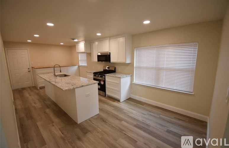 A kitchen with a granite countertop and wooden flooring.