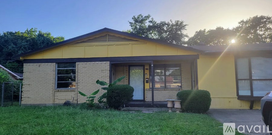 A yellow house with a black roof and a green lawn in front.