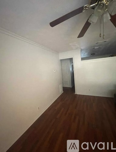 A room with a ceiling fan and wooden flooring.