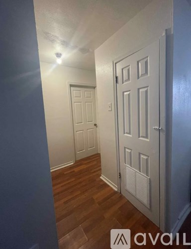 A hallway with two doors and a wooden floor.