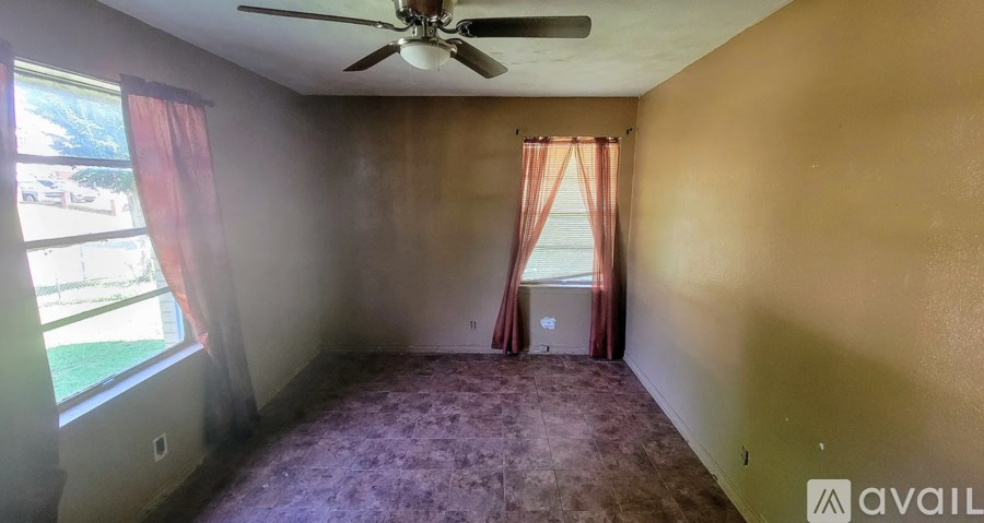 A room with a ceiling fan and a window with curtains.