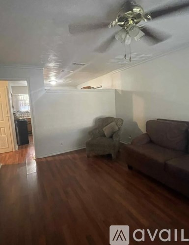 A living room with a brown couch and a fan.