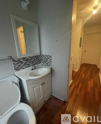 A bathroom with a toilet, sink, and mirror.