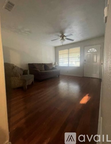 A living room with a couch, chair, and a fan.