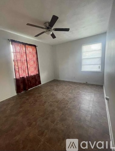 A room with a ceiling fan and a window with curtains.