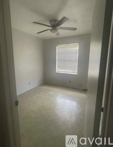 A room with a ceiling fan and a window with blinds.