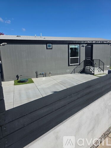 A grey building with a black door and a small window on the side.