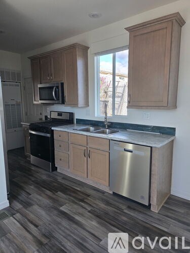A kitchen with wooden cabinets and a stainless steel dishwasher.