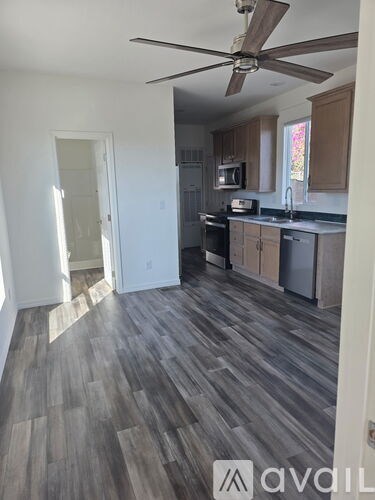A kitchen with a fan and wooden floors.