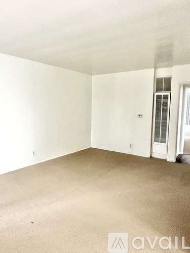 A room with a carpeted floor and a door on the right side.