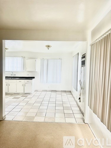 A kitchen with white cabinets and a white tile floor.