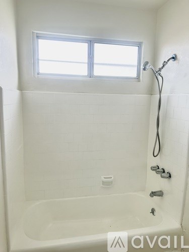 A white bathroom with a tub and a window.