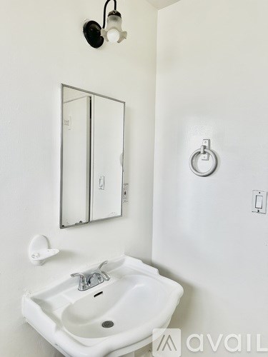 A white sink in a bathroom with a mirror and a light switch.