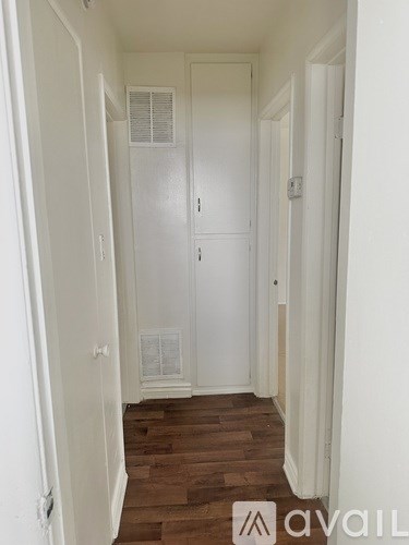 A hallway with a white door and wooden floors.