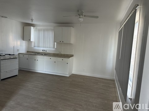 A spacious kitchen with white cabinets and a wooden floor.