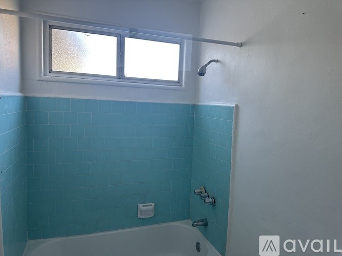 A bathroom with a blue tiled shower and a white tub.