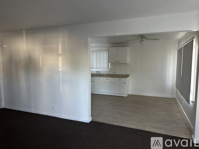 A spacious room with a kitchen area in the background.