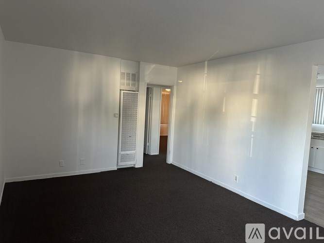 A spacious room with white walls and a black carpet.