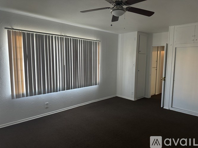 A room with a ceiling fan and a window with blinds.