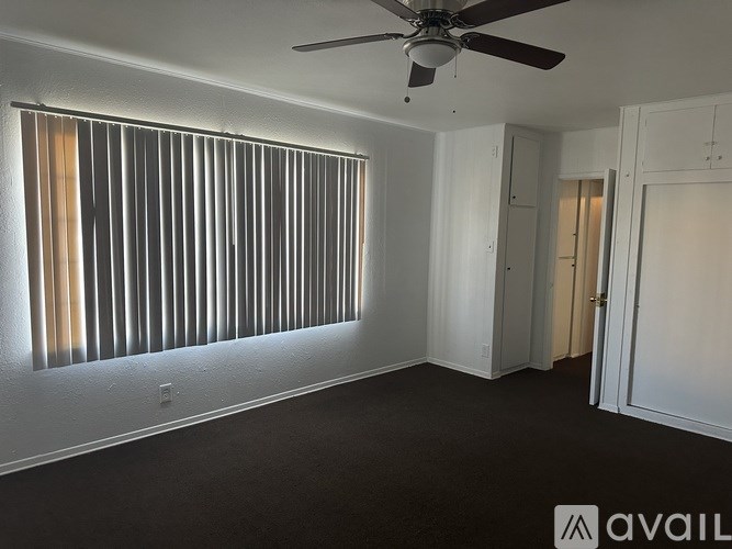 A room with a ceiling fan and a window with blinds.