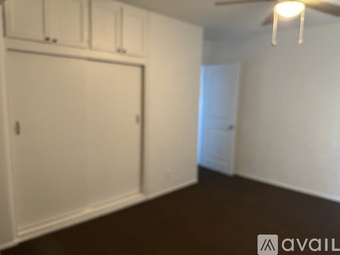 A room with a white door and a ceiling fan.