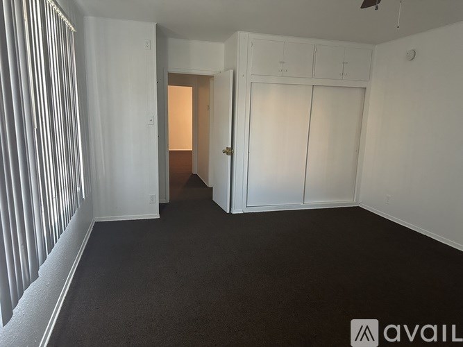 A room with a carpeted floor and white walls, with a doorway leading to another room.