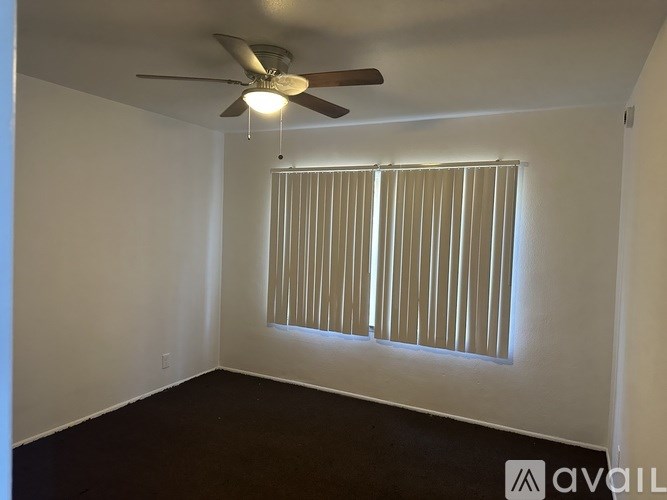 A room with a ceiling fan and a window with blinds.