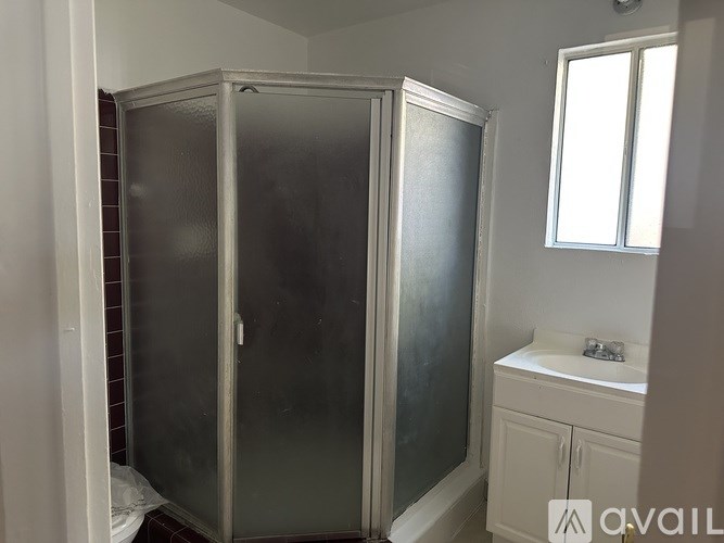 A bathroom with a glass shower door and a white sink vanity.