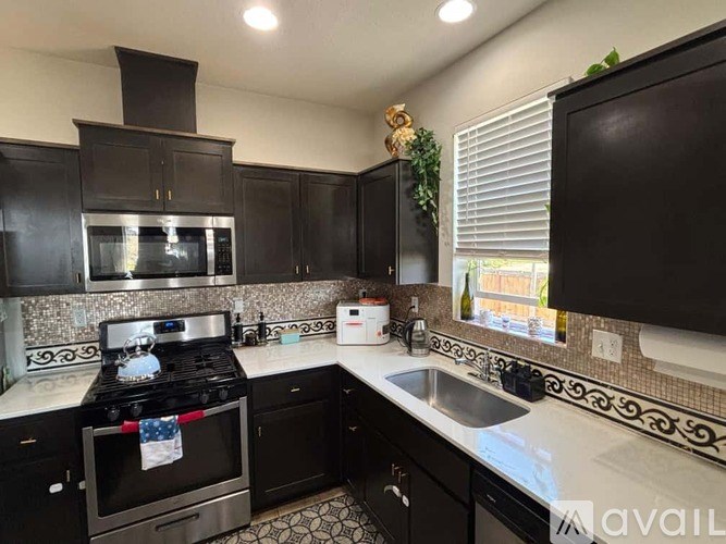 A kitchen with black cabinets and a stove top oven.