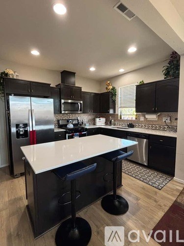 A modern kitchen with a white island and black cabinets.