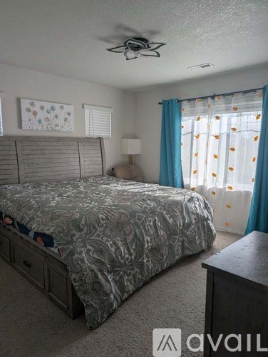 A bedroom with a bed, nightstand, and window with curtains.