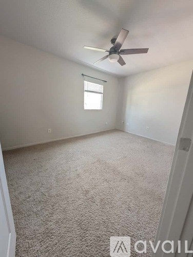 A room with a carpeted floor and a ceiling fan.