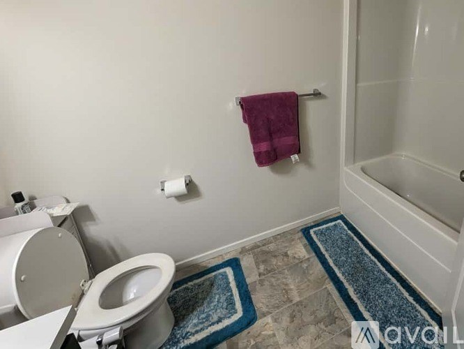 A bathroom with a toilet, a towel, and a mat.