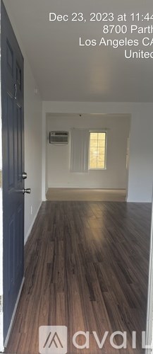 A room with wooden flooring and a door on the left side.